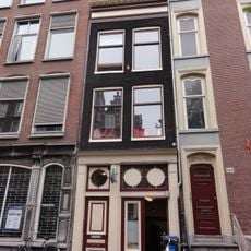 Huis met gevel onder rechte klossenlijst waarop een rondbogige dakkapel