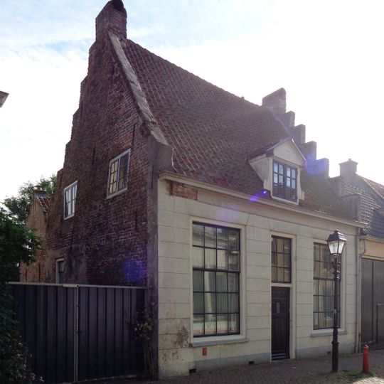Pand met begane-grond met hoog zadeldak, evenwijdig aan de straat tussen trapgevels, waarvan de linker verminkt