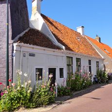 Laag pandje onder dwarskap tussen geveltoppen, bekroond door schoorsteen met dekplaat