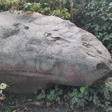 A rock with footprints in it and an inscription.