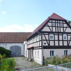 Wohnstallhaus und Stallscheune eines Gehöfts, davor Gedenkstein für Karl Traugott Schütze Hauptstraße 14