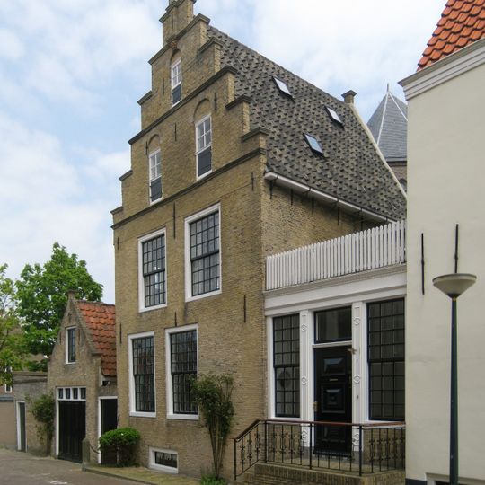 Ondiep pand onder zadeldak tussen topgevel achter en trapvormige voorgevel