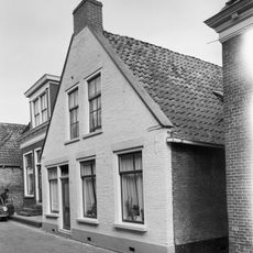 Woning onder zadeldak tegen topgevel met vlechtingen langs de zijden en aanzetlijstje