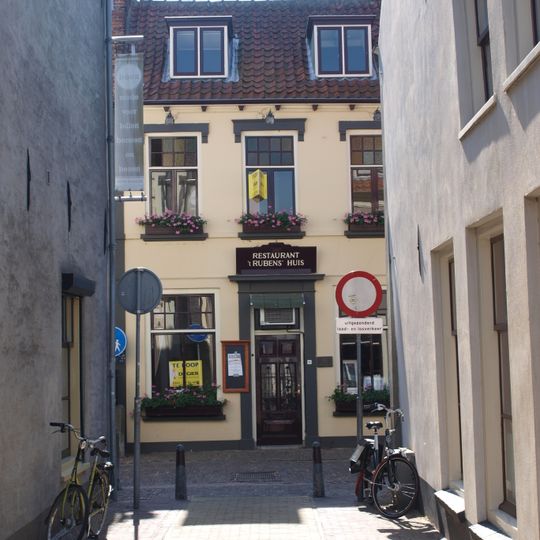 Gepleisterd eenvoudig woonhuis, grenzend aan de nauwe doorgang tot de mazijk