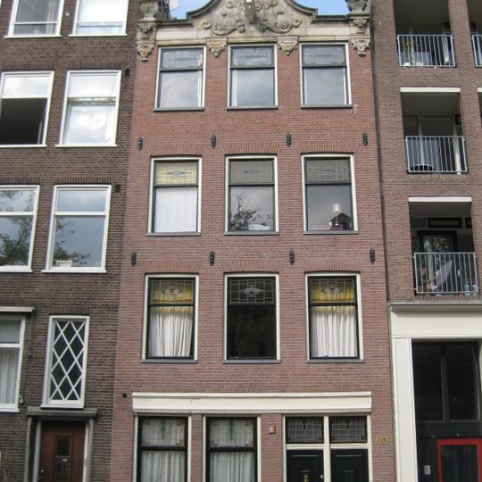 Huis waarvan de gevel wordt bekroond door een gebeeldhouwde zandstenen lijst, van elders afkomstig