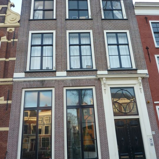 Pand met bakstenen gevel met op verdieping teruggewerkte traveeën, afgedekt met rechte kroonlijst. Deuromlijsting. Hardstenen stoep met gesmeed ijzeren hek