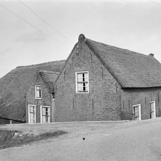 Boerderij, op T-vormige plattegrond. Woongedeelte onder rieten zadeldak, met in de vensters schuiframen met goede roedenverdeling. Stal onder rieten wolfdak
