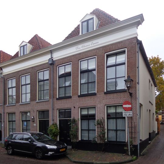 Pand met brede bakstenen gevel, forse kroonlijst en gewijzigde onderpui