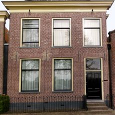 Pand met eenvoudige lijstgevel met forse lijst en dakkapel met vleugelstukken